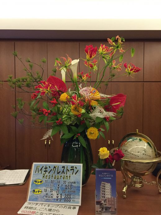 松、千両、カラー（ウェディングマーチ）、グロリオサ、アンスリウム、ラナンキュラス、アジサイ、晒ヤマシダ、紅白の水引と正月飾り